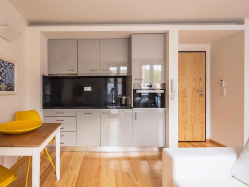 cocina con armarios blancos y mesa de madera en InSitu Trindade by Guestify, en Oporto