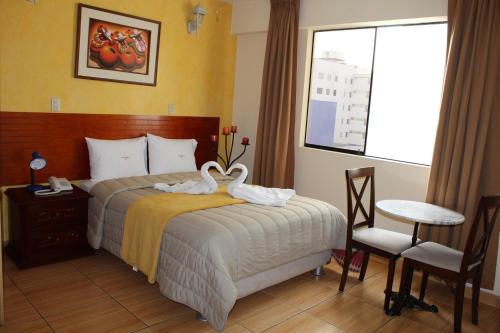 Una habitación de hotel con una cama con cisnes. en Hotel El Farolito, en Lima