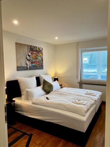 a bedroom with a large white bed with a window at Moderne Ferienwohnung in Jettingen-Scheppach