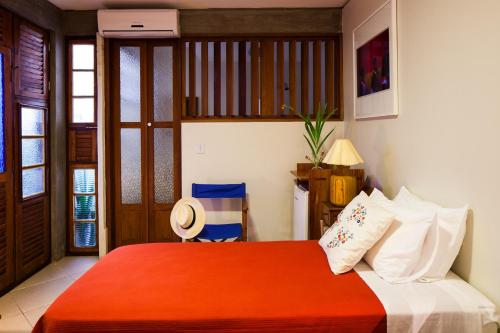 a bedroom with a bed with an orange blanket at Pousada Casa da Vitória in Salvador