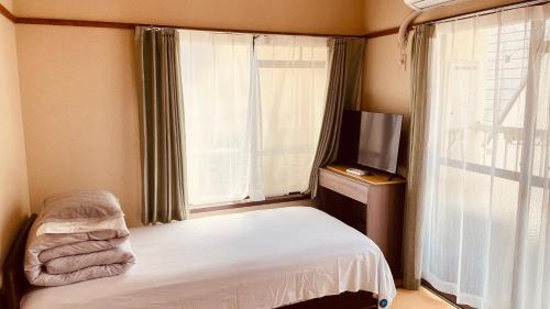 a bedroom with a bed and a tv and a window at Skytree Residence 錦糸町 駅から600M徒歩8分 in Tokyo