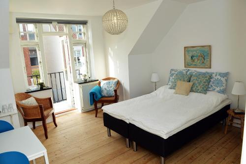 a bedroom with a bed and two chairs and a table at Sweethome Guesthouse in Esbjerg