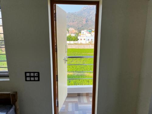 una puerta abierta con vistas a un campo verde en Poornima home stay, en Tiruvannāmalai