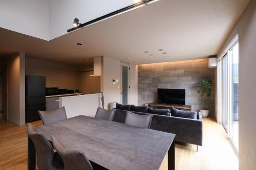 a dining room with a table and chairs and a television at 62 Fuji Petel DEUX -ドゥ- in Fujikawaguchiko