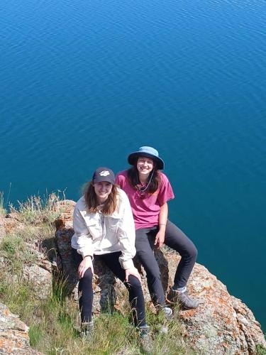 two women sitting on a rock near the water at Jusup Guest House, Hostel in Dzhangyaryk
