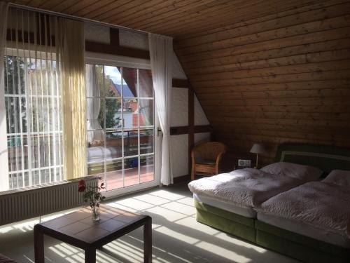 a bedroom with a bed and a table and windows at Haus Roswita in Bad Harzburg