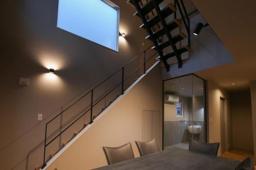 a dining room with a table with chairs and a staircase at 62 Fuji Petel DEUX -ドゥ- in Fujikawaguchiko