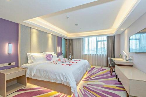 une chambre d'hôtel avec un grand lit et un bureau dans l'établissement Lavande Hotel Guangzhou Jingxi Southern Hospital Metro Station, à Canton