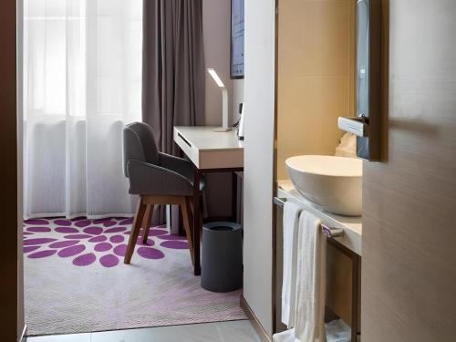 La salle de bains est pourvue d'un lavabo et d'un bureau avec une chaise. dans l'établissement Lavande Hotel Guangzhou Jingxi Southern Hospital Metro Station, à Canton