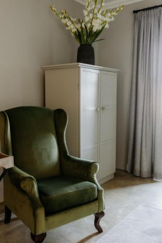 a green chair and a cabinet with a vase of flowers at Fancy Fritz B&B in Swakopmund