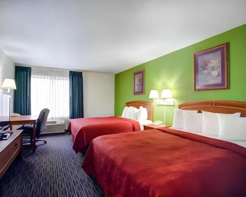 a hotel room with two beds and a desk at Quality Inn & Suites Airport in Austin