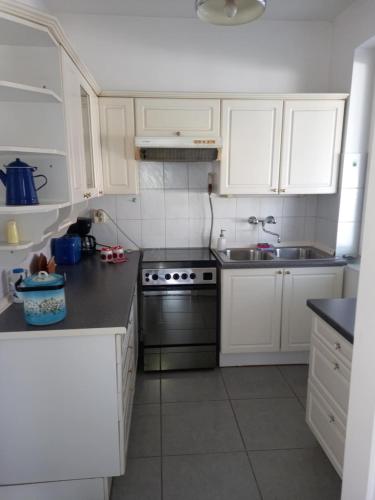 a kitchen with white cabinets and a stove and a sink at Sára Vendégház in Szentes