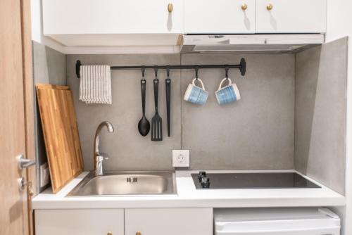 a kitchen with a sink and utensils on the wall at Olesia Rooms in Naousa in Naousa