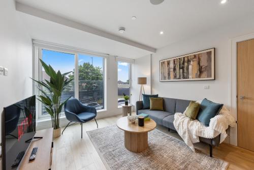 a living room with a couch and a table at Modern & Cozy 2-Bedroom Apartment plus Parking, Gym, Cinema, Games Room, Workspace in New Malden