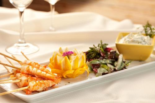 a plate of food with shrimp and vegetables on a table at Mercure Salvador Rio Vermelho in Salvador