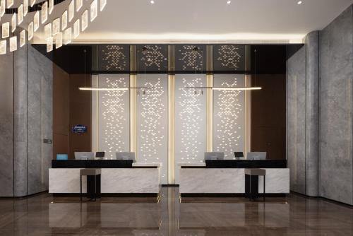 a lobby with two desks and a glass wall at Hampton By Hilton Dongguan Nancheng Xiping in Baima