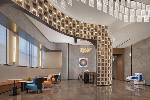 a lobby with a brick wall and tables and chairs at Hampton By Hilton Dongguan Nancheng Xiping in Baima