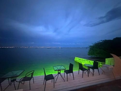 a group of chairs and tables on a deck overlooking the water at Baan Sailboat Beach Kohlarn in Ko Larn