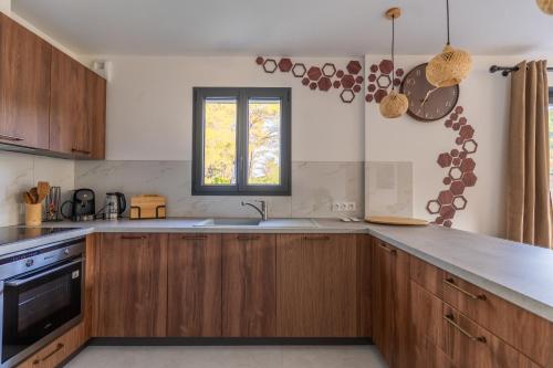 a kitchen with wooden cabinets and a window at Villa le Jas de Bali - 4chambres - Piscine et parking privé in Figanières