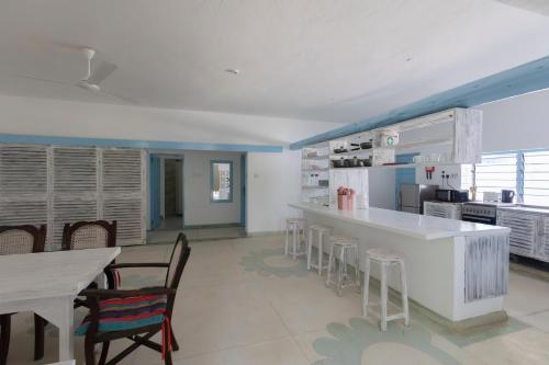 a kitchen with a counter and chairs and a table at Allamanda Boutique Hostel in Galu