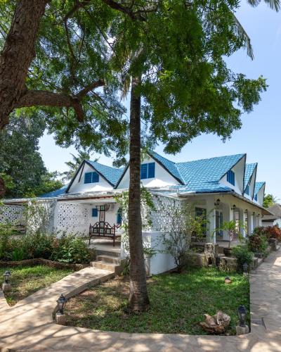 a white house with a blue roof at Allamanda Boutique Hostel in Galu