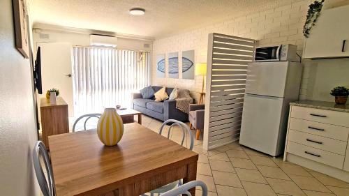a kitchen and living room with a table and a refrigerator at 85 on First - Sawtell Apartments in Sawtell