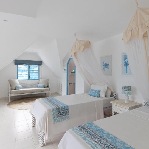 a white room with two beds and a couch at Allamanda Boutique Hostel in Galu