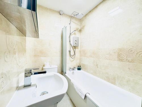 une salle de bain blanche avec un lavabo et une baignoire dans l'établissement City Centre Escape with Private Garden, à Édimbourg