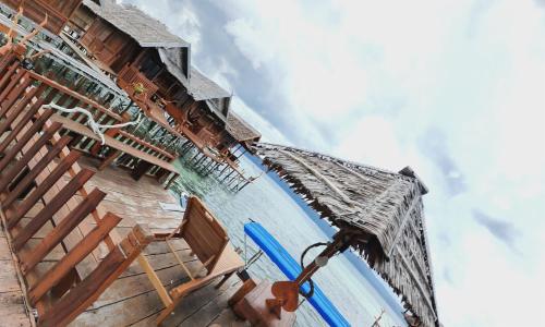 a swimming pool with an umbrella and some chairs at Happy Homestay Arborek in Besir