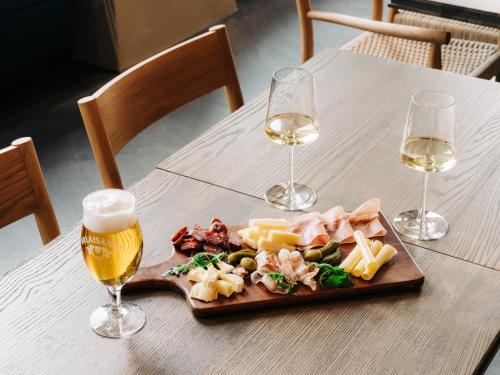 a plate of food and two glasses of wine on a table at KURVE Apartments & Lounge in Adelboden