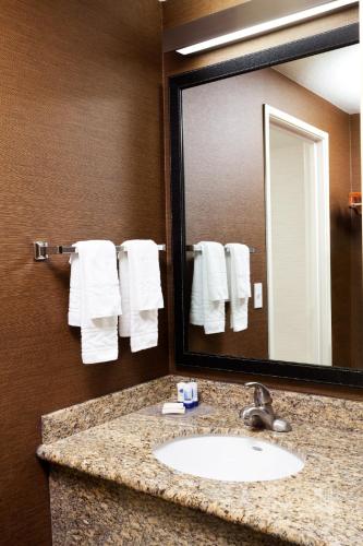 a bathroom with a sink and a mirror and towels at Country Inn & Suites by Radisson, Phoenix Airport, AZ in Phoenix