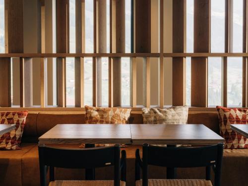 a table and chairs in a restaurant with windows at KURVE Apartments & Lounge in Adelboden