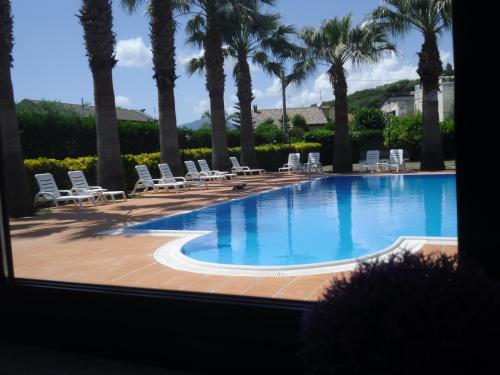 a swimming pool with chairs and palm trees at Villa Laura Residence Hotel Apartments & Studios in Ascea