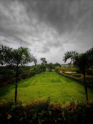 a large field with palm trees on a cloudy day at The Clouds Resort Goa in Goa