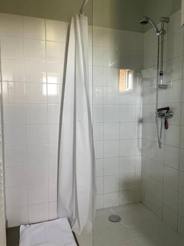 a shower with a white shower curtain in a bathroom at La Maison de la Mare in Doudeville