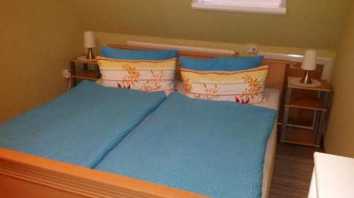 Schlafzimmer mit einem Bett mit blauer Bettwäsche und Kissen in der Unterkunft Österdeichstrich in Oesterdeichstrich