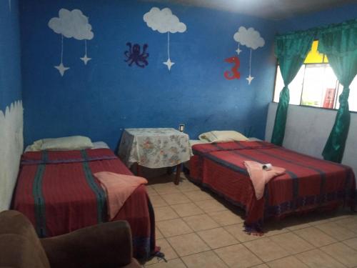 a bedroom with two beds and a table and clouds at House the Cats in Panajachel
