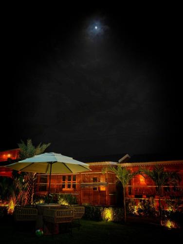 a building with an umbrella and chairs in front of it at night at The Clouds Resort Goa in Goa