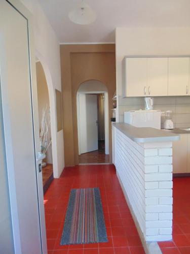 a kitchen with white cabinets and a red tile floor at Villa Lasta in Drasnice
