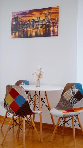 two chairs and a white table with a picture on the wall at Apartment SOFI Belville in Novi Beograd