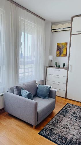 a living room with a couch in front of a window at Apartment SOFI Belville in Novi Beograd