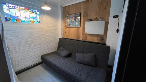 a grey couch in a room with a window at It Wûnder in Oude Bildtzijl
