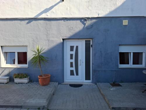 a blue building with a door and a potted plant at Cantinho Acolhedor in Arrabal