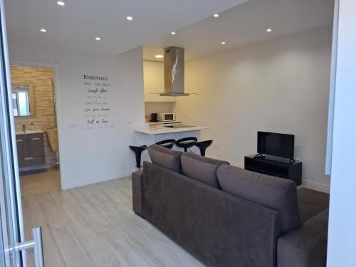 a living room with a couch and a kitchen at Cantinho Acolhedor in Arrabal
