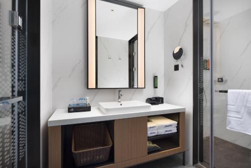 a bathroom with a sink and a mirror at Hampton By Hilton Dongguan Nancheng Xiping in Baima