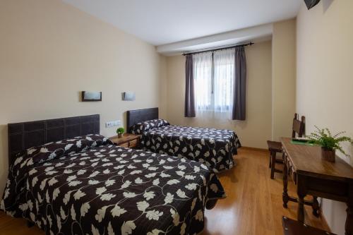 a room with two beds and a table and a desk at Hostal LaPerdiz in Sonseca