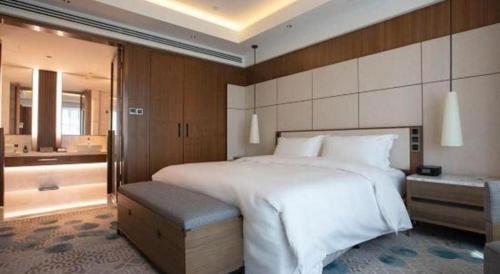 a bedroom with a large white bed and a bathroom at Empark Grand Hotel Fuzhou in Fuzhou