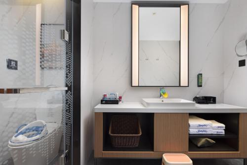 a bathroom with a sink and a mirror at Hampton By Hilton Dongguan Nancheng Xiping in Baima