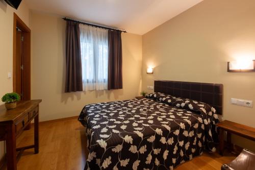 a bedroom with a bed with a black and white comforter at Hostal LaPerdiz in Sonseca