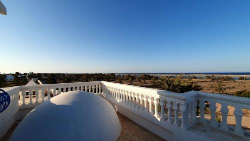 a white balcony with a view of the beach at maison d hôte rêve de désert jerba in Al Ḩaddādah